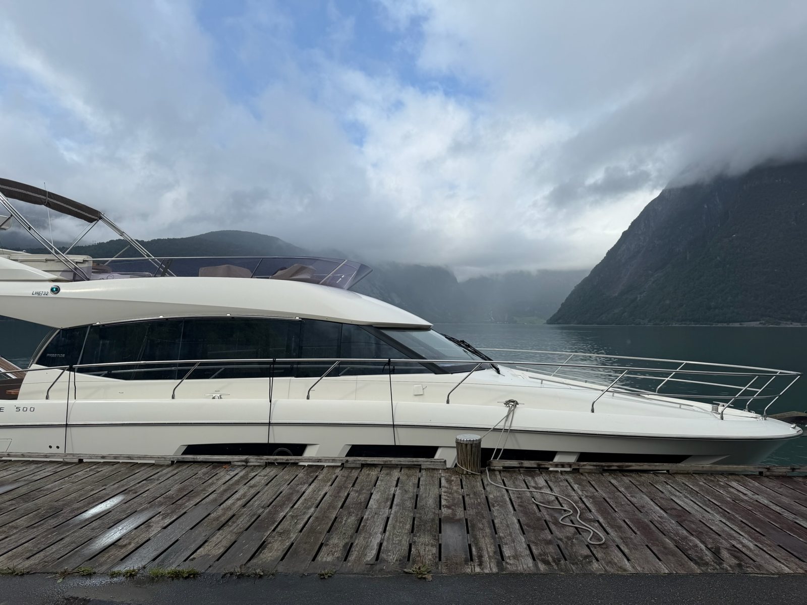 Fjord Queen alongside the old wooden quay, clouds resting halfway down the fjord walls